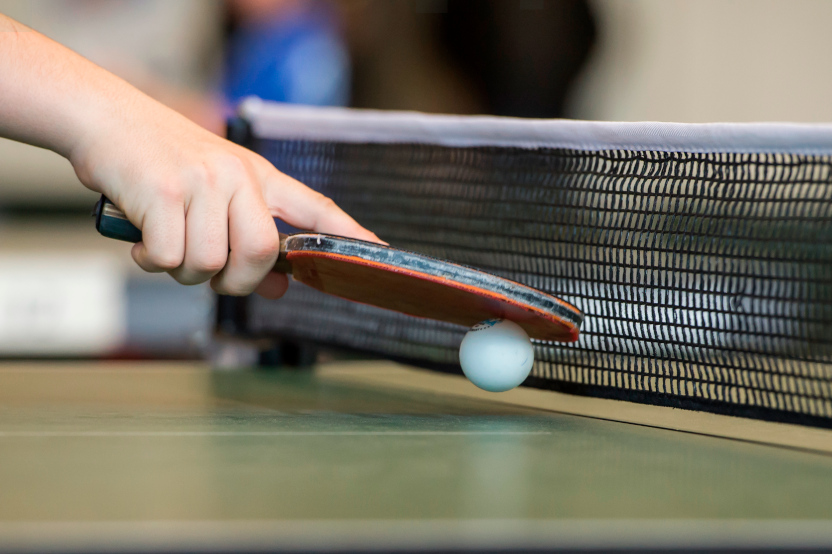 Tischtennisschläger mit Ball am Netz